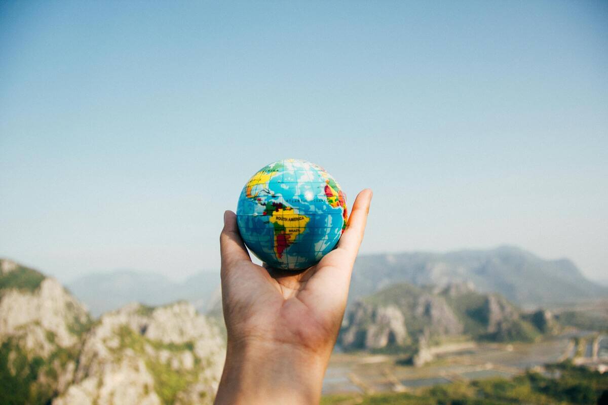 Hand holding travel globe looking at scenic view