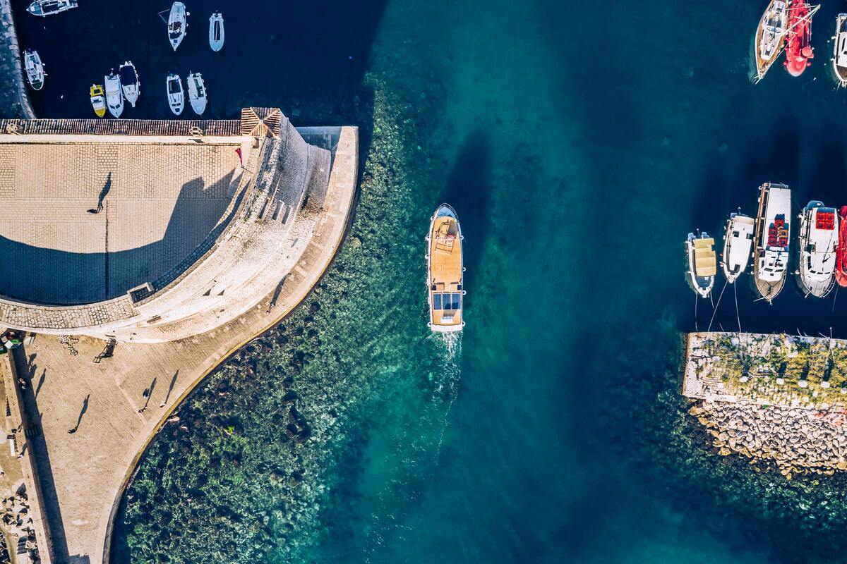 Aerial view of Dubrovnik harbour with boats and turquoise water along the Adriatic coast