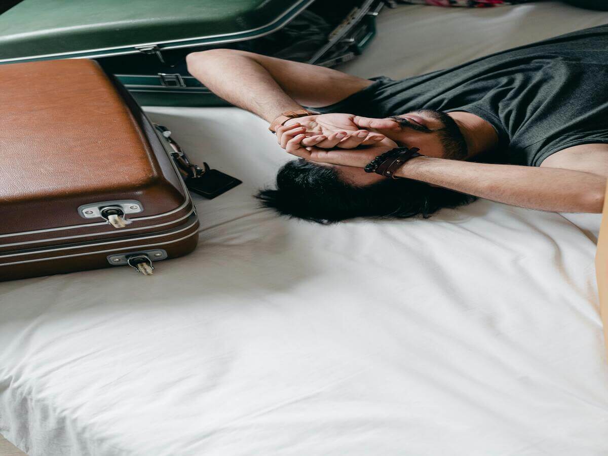 Traveller feeling overwhelmed while packing for a Europe trip with suitcases on bed