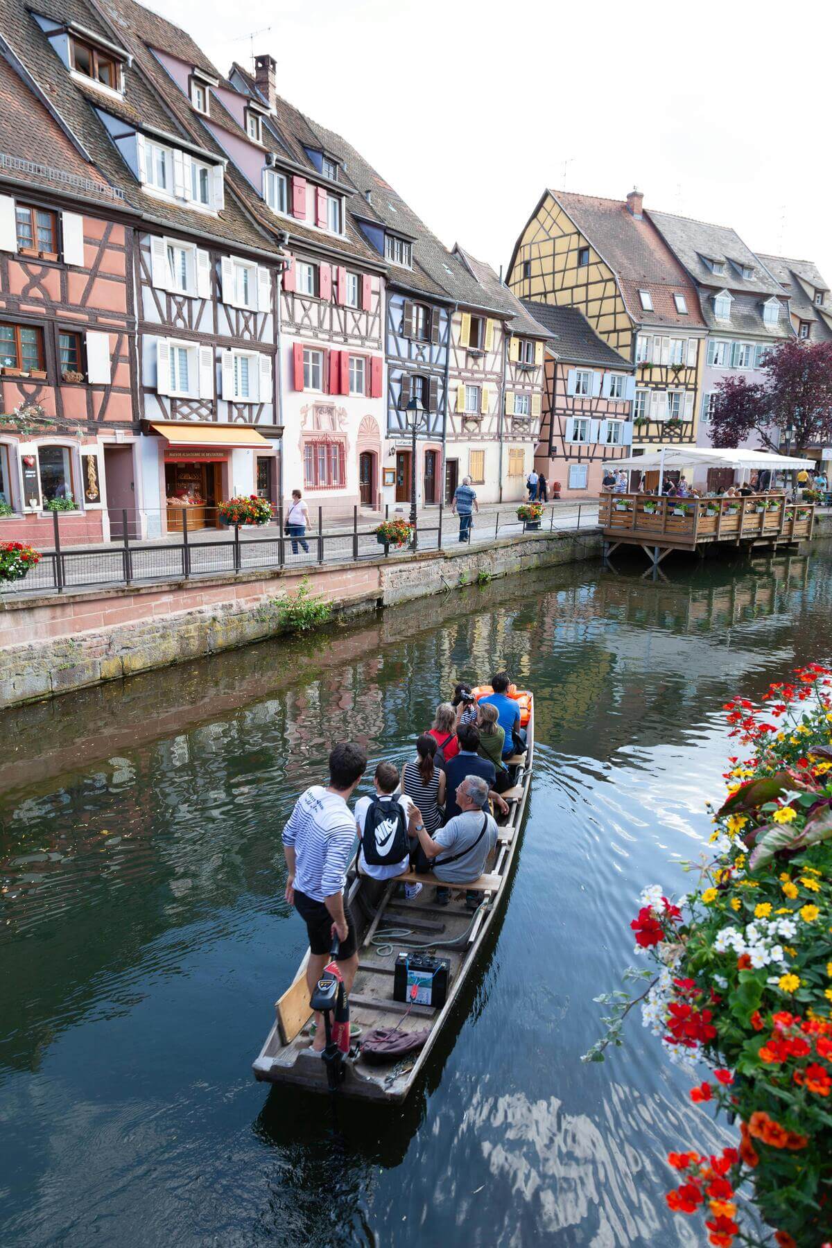 Tourists on a canal boat in a picturesque European town with colourful houses and flowers