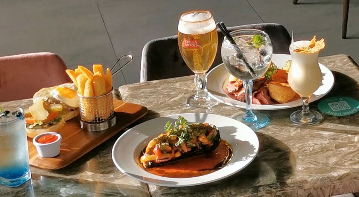 European dining table with cocktails, burger and plated dish, highlighting food experiences while travelling 
