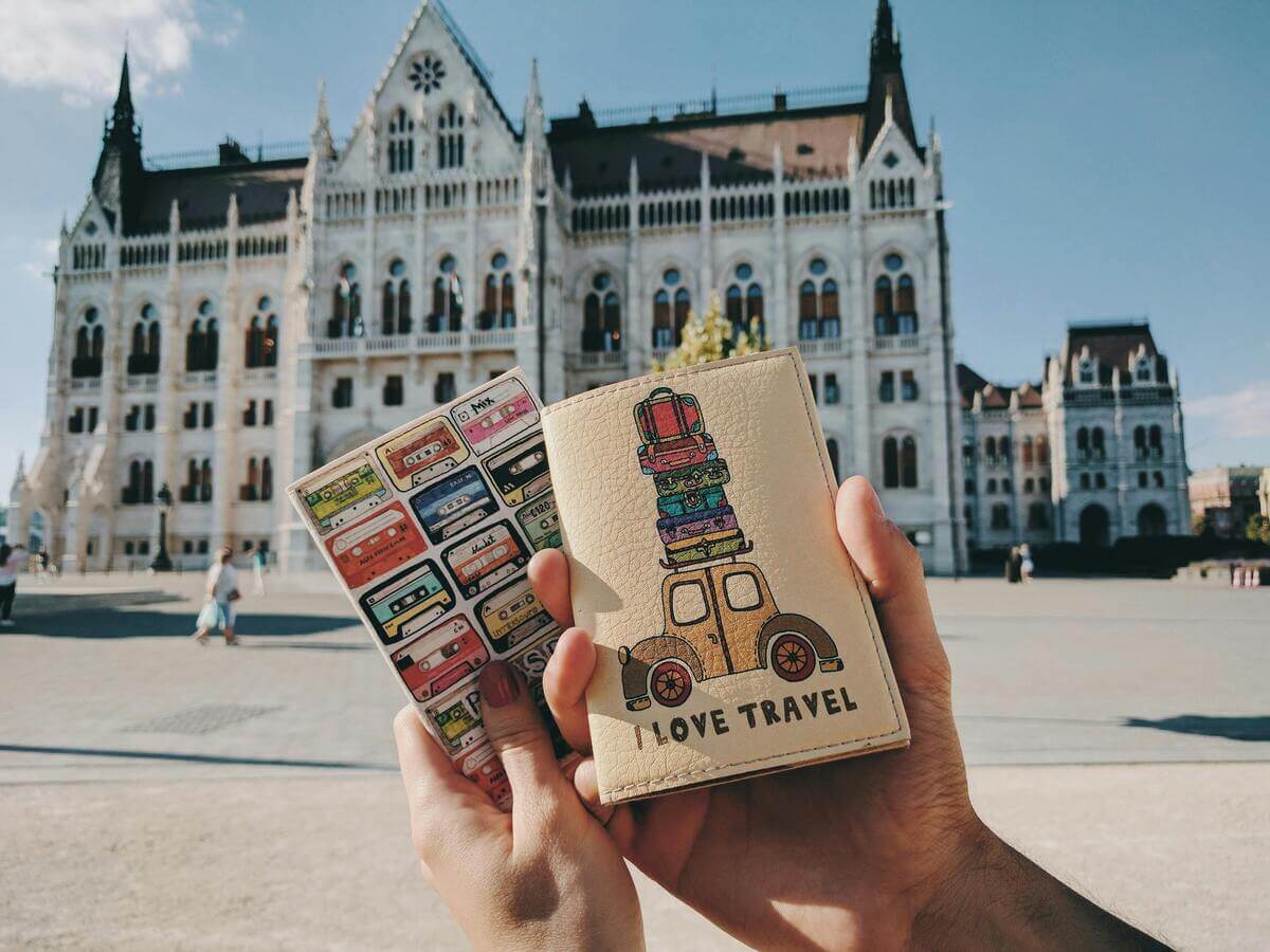 Holding passport and travel tickets in front of a European landmark, symbolising travel preparation