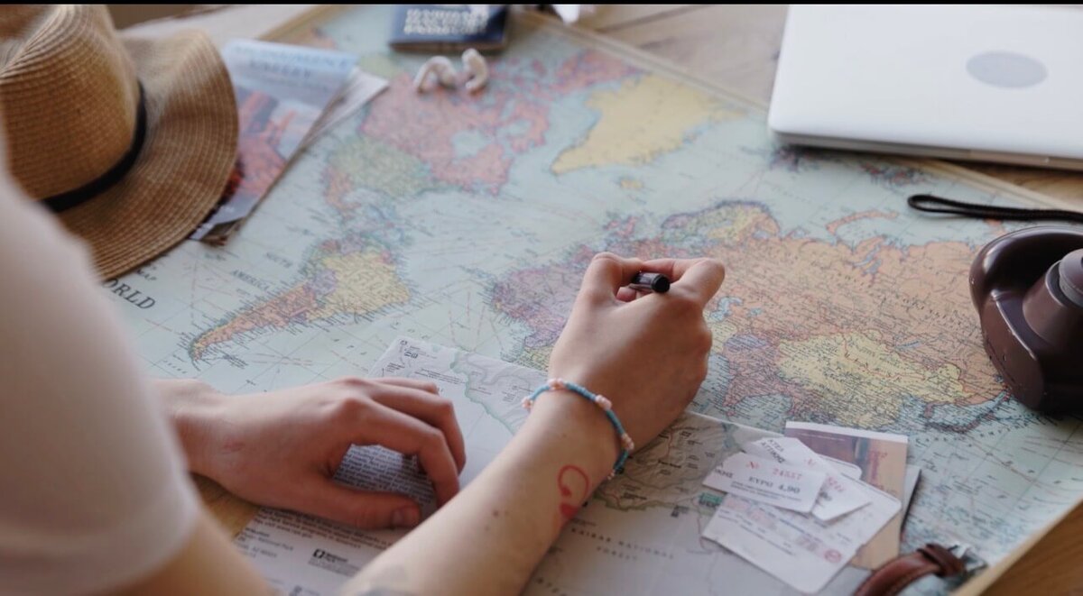 Person planning Europe trip with map, tickets and notes, organising itinerary and travel routes